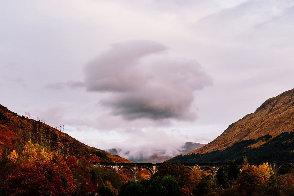 The Glenfinnan Viaduct beneath russet autumn hillsides and a low pink cloud, Scottish Highlands