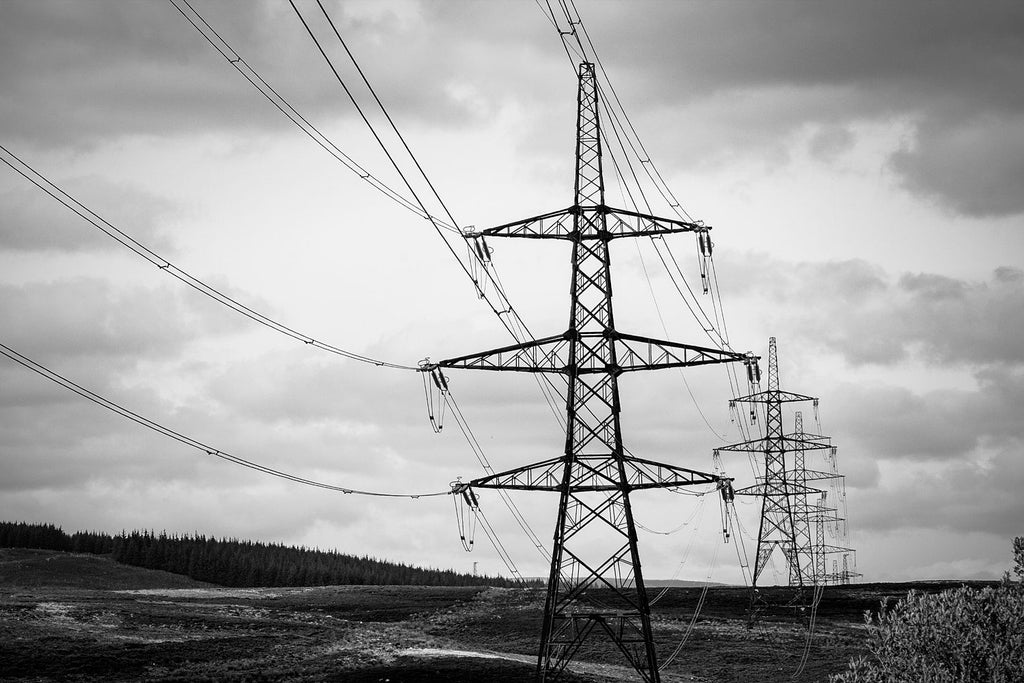 Black and white photograph of electricity pylons crossing open moorland